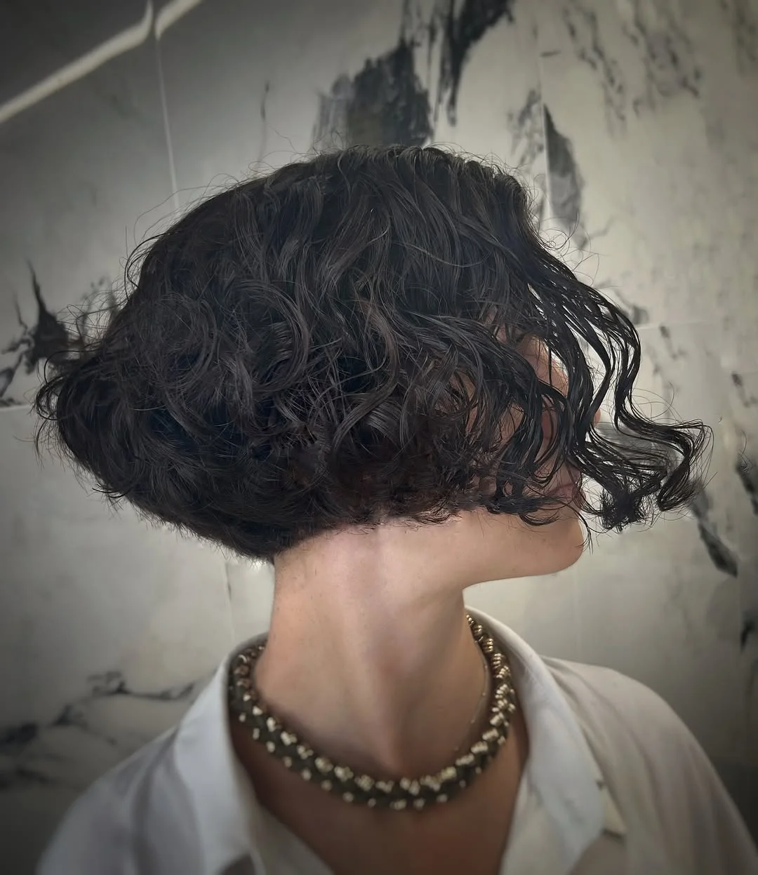 chic summer haircut 2026 Wet-Look Curly French Bob With Sculpted Ends