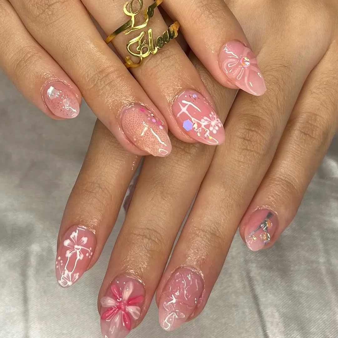 pink summer nails 2026 Sheer Pink Almond Nails With White Florals And Iridescent Details