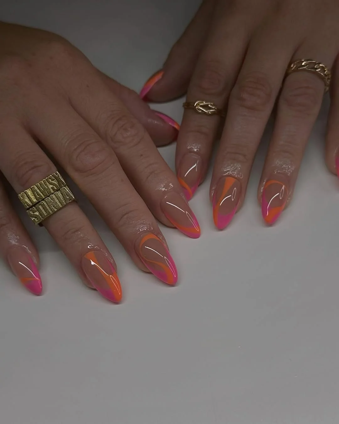 trendy summer nails 2026 Neon Pink And Orange Almond Tips With A Glossy Nude Base