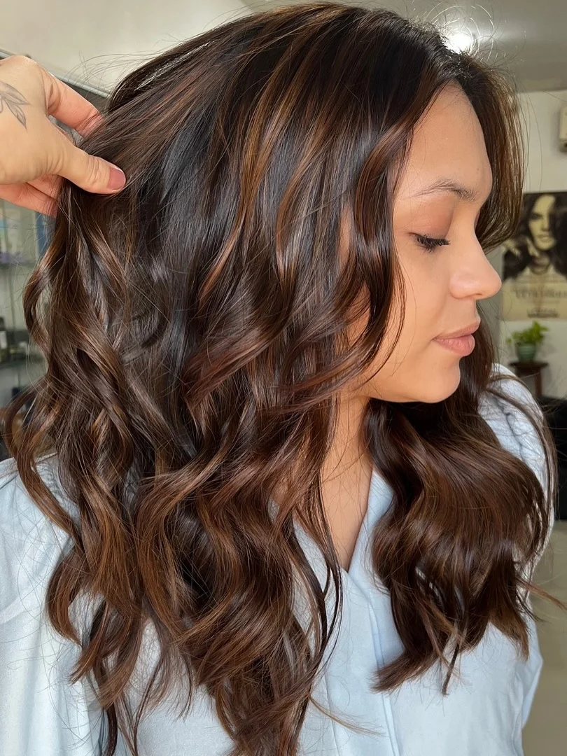 warm summer brunette hair color 2026 Cinnamon Brunette Curls With Soft Face-Framing Light